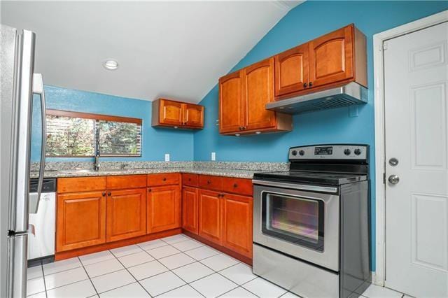 kitchen featuring light stone counters, light tile patterned floors, stainless steel appliances, and vaulted ceiling