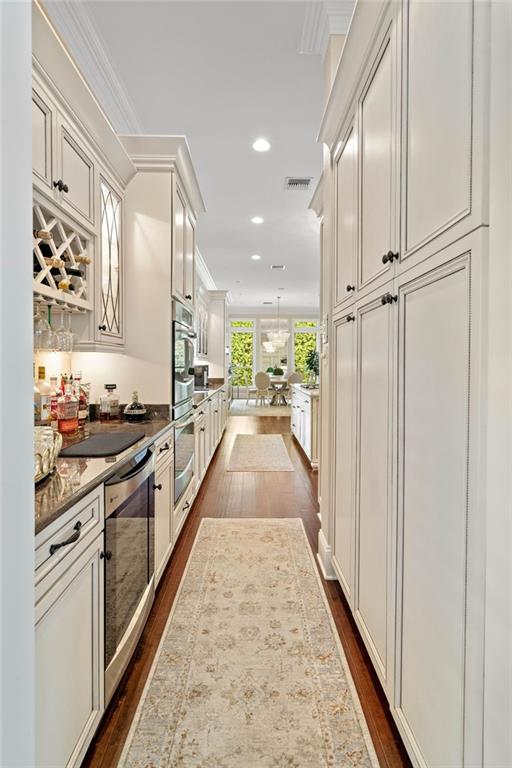 kitchen with dark hardwood / wood-style floors, light stone countertops, and ornamental molding