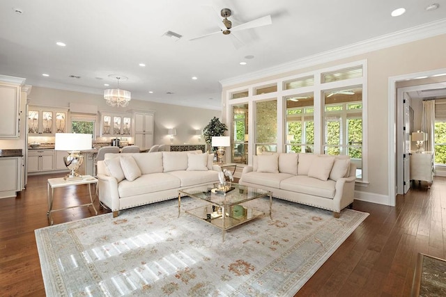 living room featuring ceiling fan with notable chandelier, crown molding, and dark wood-type flooring