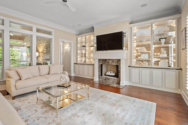 living room featuring a fireplace, wood-type flooring, ceiling fan, and ornamental molding