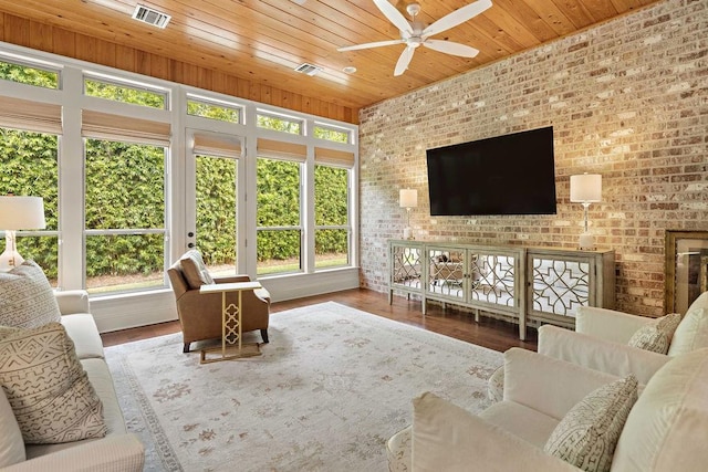 living room with hardwood / wood-style flooring, ceiling fan, wood ceiling, and brick wall