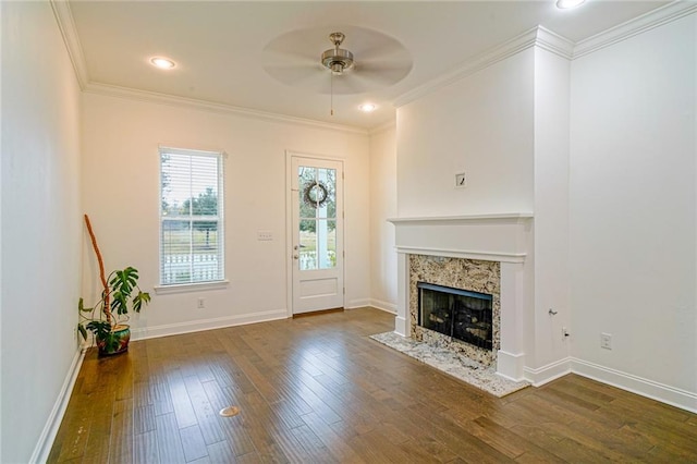 unfurnished living room with crown molding, a fireplace, dark hardwood / wood-style floors, and ceiling fan