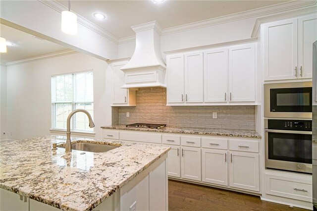 kitchen featuring an island with sink, appliances with stainless steel finishes, sink, and custom range hood