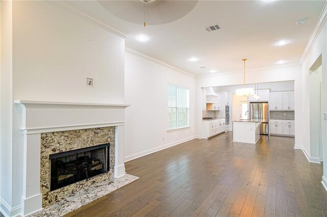 unfurnished living room featuring dark hardwood / wood-style flooring, crown molding, a fireplace, and ceiling fan