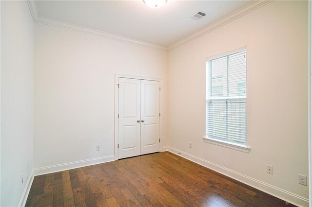 empty room with dark hardwood / wood-style flooring, a wealth of natural light, and ornamental molding