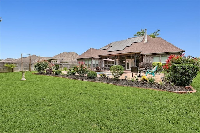 back of house featuring a lawn, a patio area, and solar panels