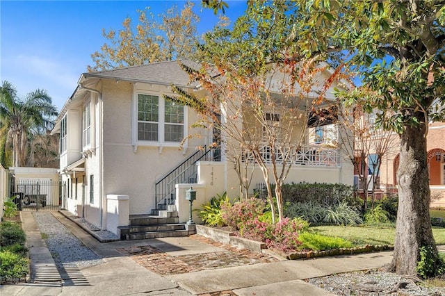 view of front of house featuring stairs, fence, and stucco siding