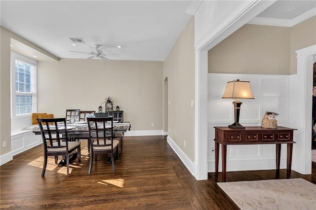 dining room featuring arched walkways, visible vents, a decorative wall, ceiling fan, and wood finished floors