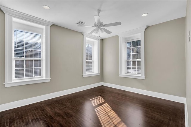 unfurnished room featuring a healthy amount of sunlight, dark wood finished floors, and baseboards