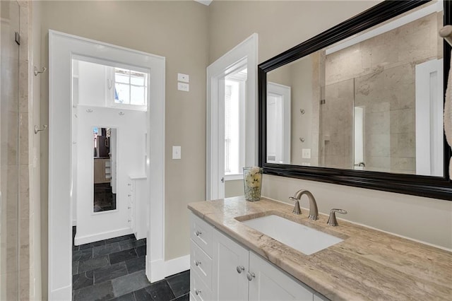 bathroom with stone finish flooring, baseboards, and vanity