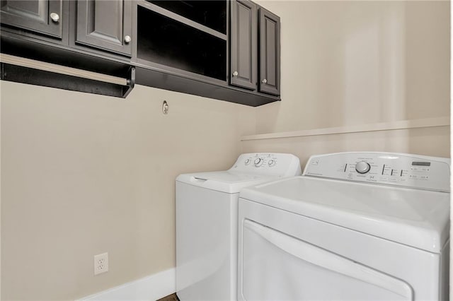 clothes washing area with independent washer and dryer and cabinet space