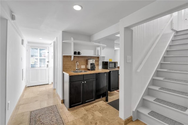 bar featuring a sink, baseboards, stairs, decorative backsplash, and stainless steel microwave