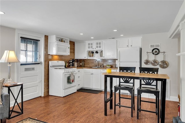 kitchen featuring white appliances, dark wood-type flooring, a sink, visible vents, and white cabinetry