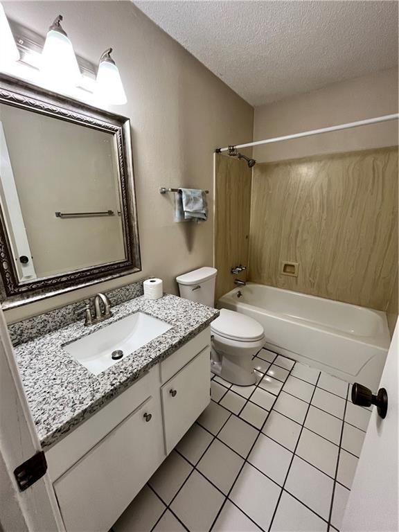 full bathroom featuring tile patterned floors, toilet, a textured ceiling, shower / bathtub combination, and vanity