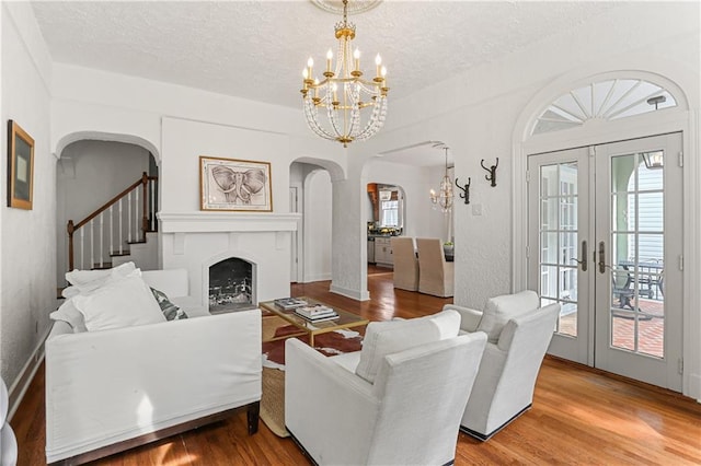 living room featuring wood-type flooring, a textured ceiling, a chandelier, and french doors