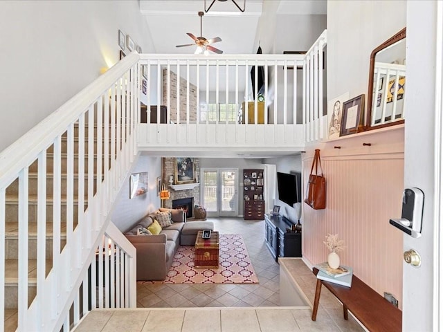 living room with high vaulted ceiling, a stone fireplace, tile patterned floors, and ceiling fan