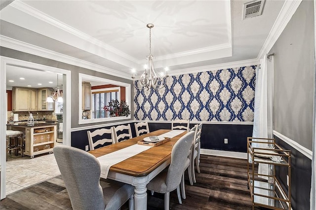 dining area with a raised ceiling, dark hardwood / wood-style flooring, an inviting chandelier, and ornamental molding