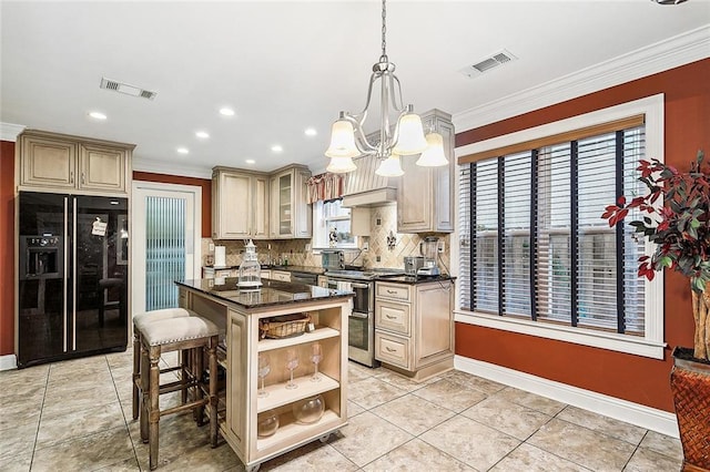 kitchen featuring black fridge, decorative light fixtures, double oven range, cream cabinetry, and a breakfast bar area