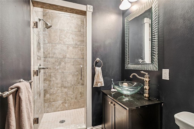 bathroom featuring a tile shower, vanity, and toilet