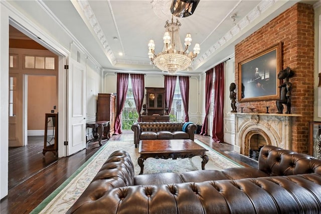 interior space with a tray ceiling, crown molding, a notable chandelier, dark hardwood / wood-style floors, and a fireplace