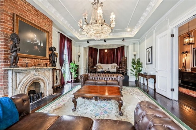 sitting room featuring an inviting chandelier, hardwood / wood-style floors, crown molding, and a fireplace