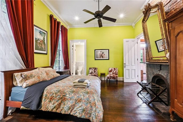 bedroom featuring connected bathroom, ceiling fan, ornamental molding, and a stone fireplace