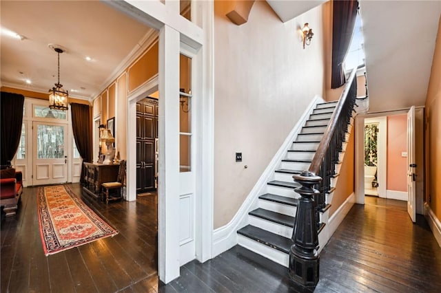 stairway featuring hardwood / wood-style flooring, a notable chandelier, and ornamental molding