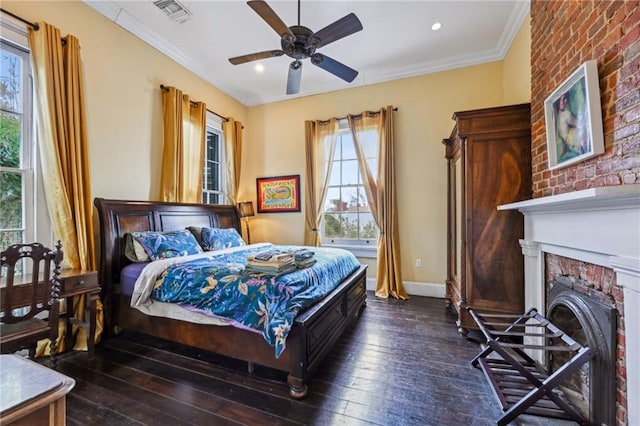 bedroom with dark wood-type flooring, ceiling fan, ornamental molding, and a brick fireplace