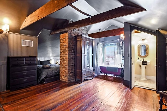 bedroom featuring connected bathroom, wood walls, lofted ceiling with beams, and dark wood-type flooring