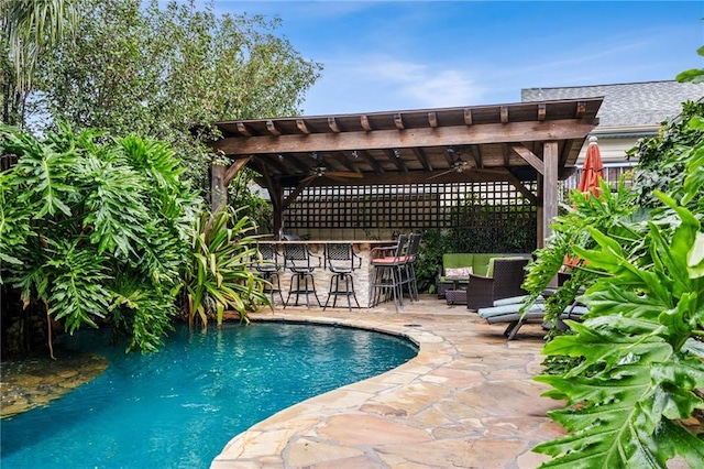 view of swimming pool featuring exterior bar, a pergola, and a patio