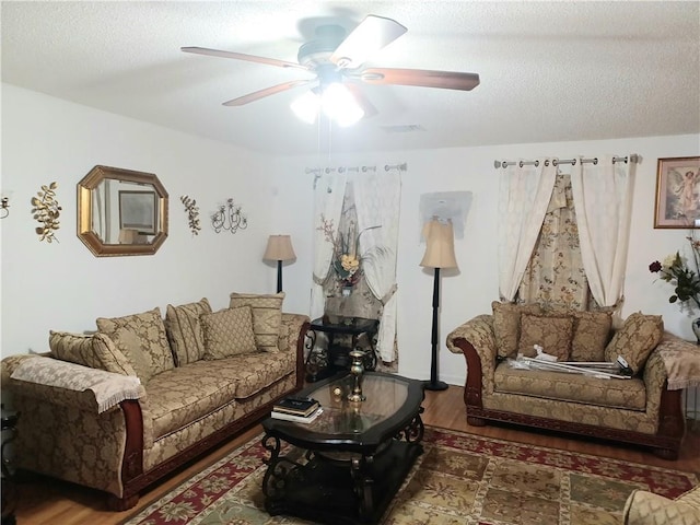 living room with a textured ceiling, dark hardwood / wood-style floors, and ceiling fan