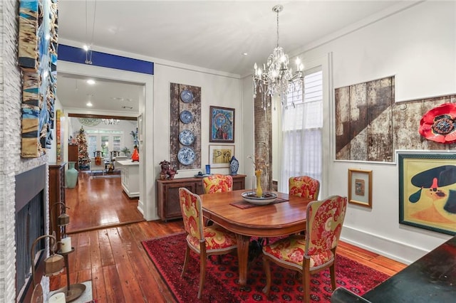 dining space featuring a fireplace, dark hardwood / wood-style floors, a chandelier, and ornamental molding