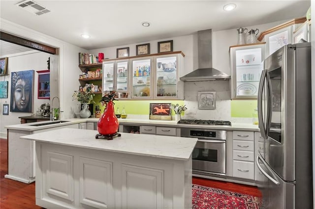 kitchen with white cabinets, wall chimney range hood, light stone counters, kitchen peninsula, and stainless steel appliances