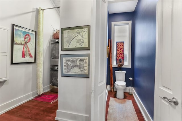 bathroom featuring wood-type flooring, toilet, and stacked washer and clothes dryer