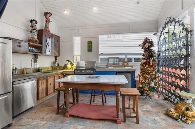 kitchen with sink, appliances with stainless steel finishes, and vaulted ceiling