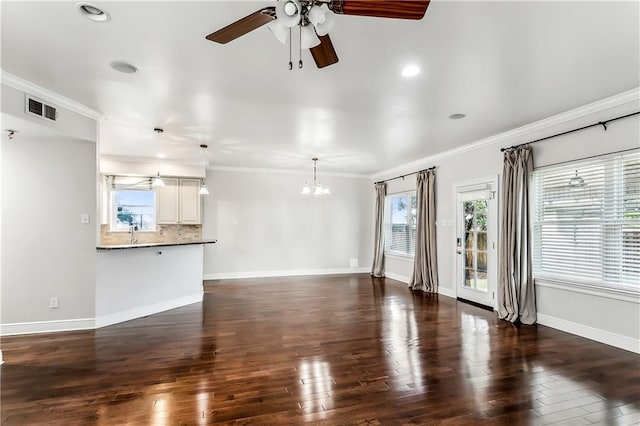 unfurnished living room featuring a wealth of natural light, dark wood-type flooring, and ornamental molding