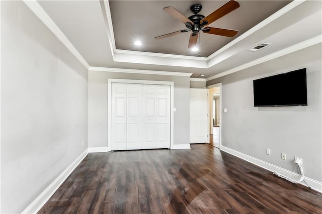 unfurnished bedroom with a raised ceiling, ceiling fan, a closet, and ornamental molding