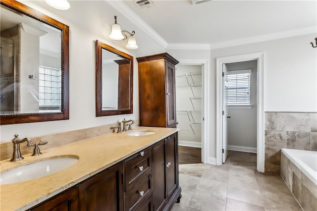 bathroom with tiled bath, plenty of natural light, vanity, and ornamental molding