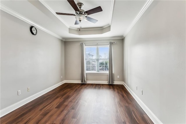 unfurnished room featuring a tray ceiling, crown molding, ceiling fan, and dark wood-type flooring