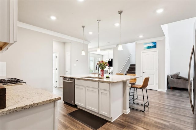 kitchen featuring sink, hanging light fixtures, an island with sink, appliances with stainless steel finishes, and white cabinetry