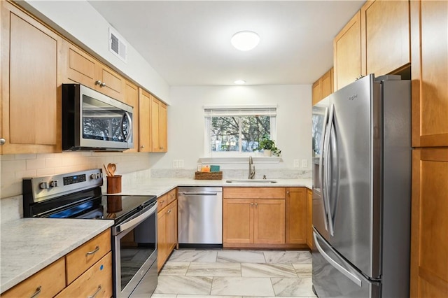 kitchen with light stone counters, sink, stainless steel appliances, and tasteful backsplash