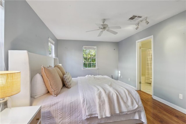 bedroom featuring ensuite bathroom, track lighting, ceiling fan, and dark hardwood / wood-style floors