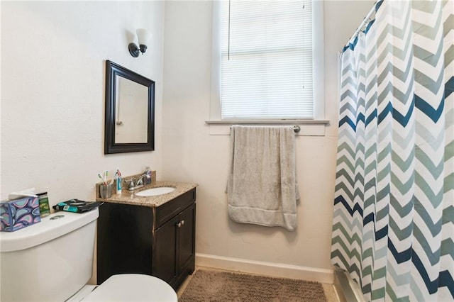 bathroom featuring toilet, vanity, and curtained shower