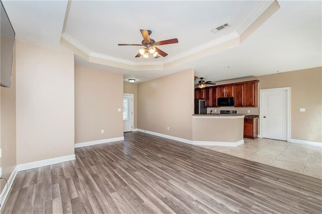 unfurnished living room with ceiling fan, light hardwood / wood-style flooring, crown molding, and a tray ceiling