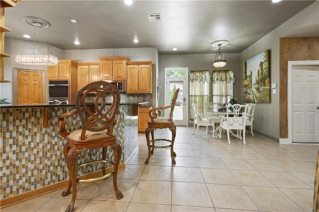 kitchen with tasteful backsplash, a chandelier, pendant lighting, light tile patterned floors, and appliances with stainless steel finishes