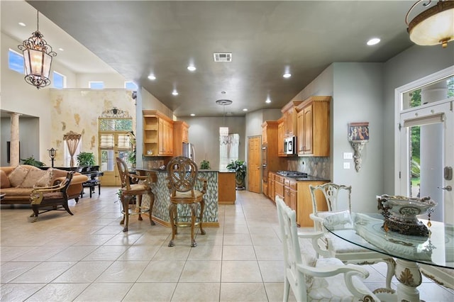 kitchen featuring a chandelier, pendant lighting, decorative backsplash, light tile patterned floors, and appliances with stainless steel finishes