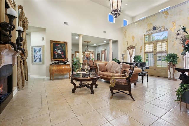 tiled living room featuring french doors, decorative columns, a notable chandelier, and a high ceiling