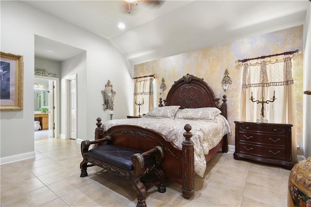 bedroom with ensuite bath, light tile patterned floors, and vaulted ceiling