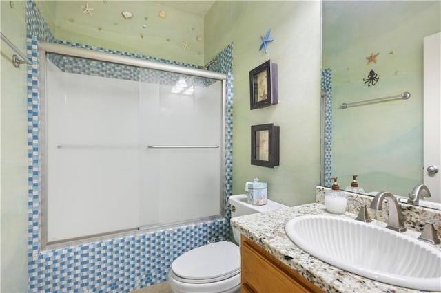 full bathroom featuring vanity, toilet, and combined bath / shower with glass door