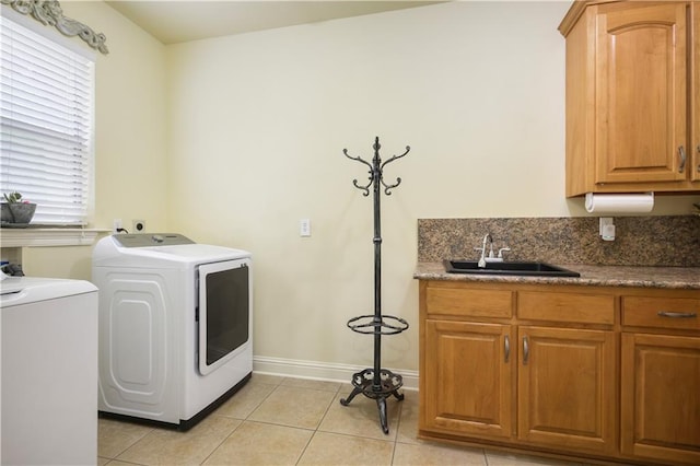 clothes washing area with light tile patterned flooring, washing machine and dryer, plenty of natural light, and sink